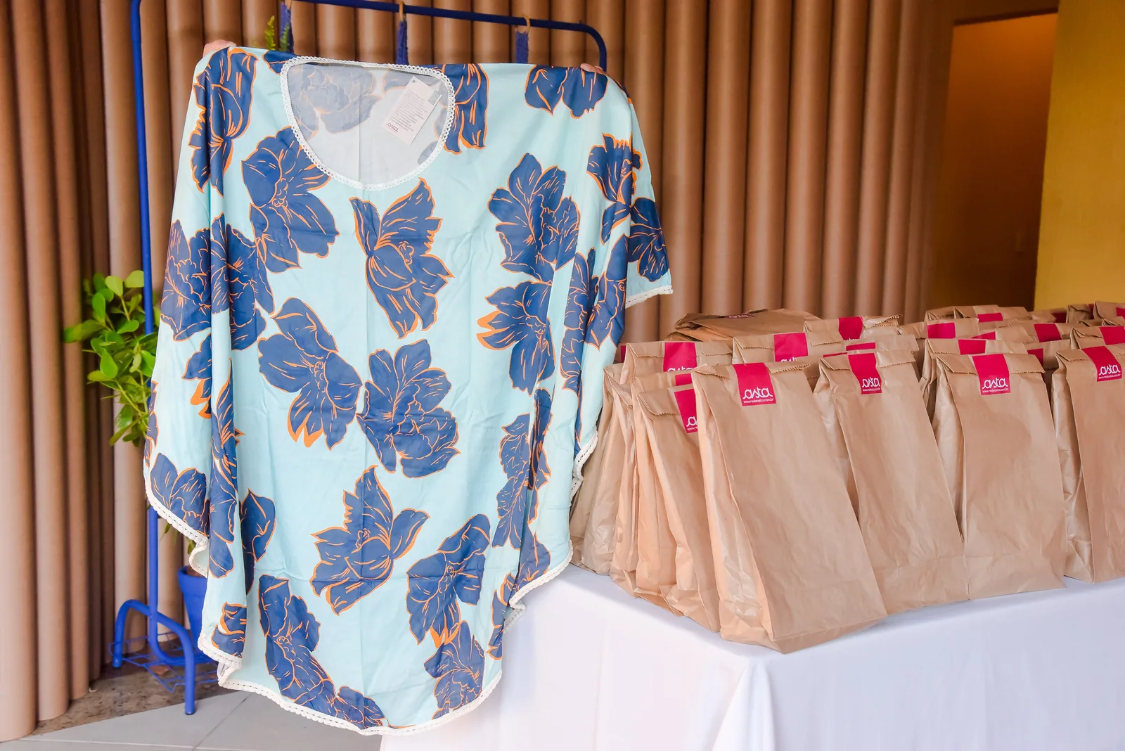A printed kaftan on a rail next to wrapped gift bags