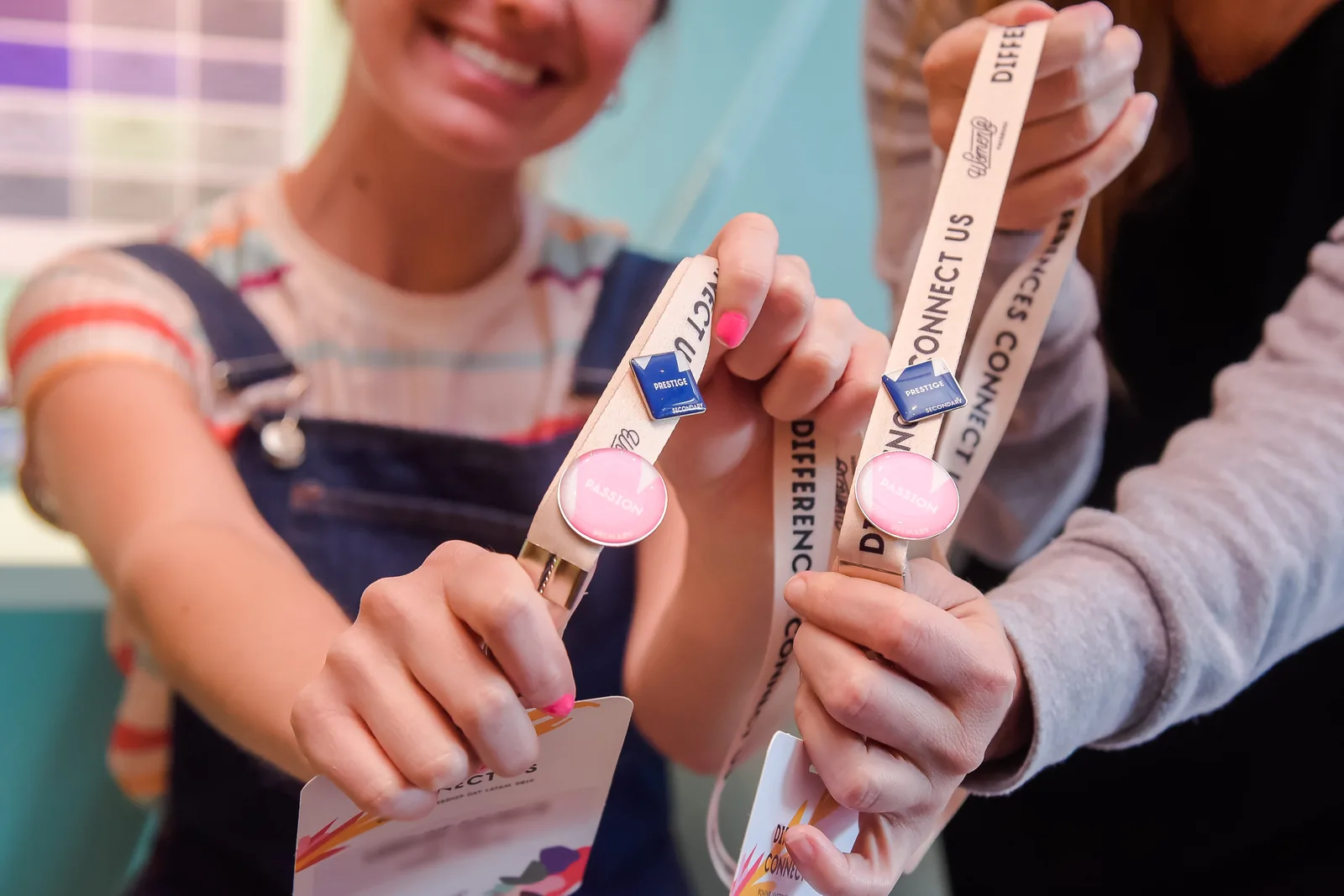 Two attendees holding their lanyards, each with a round and a square pin
