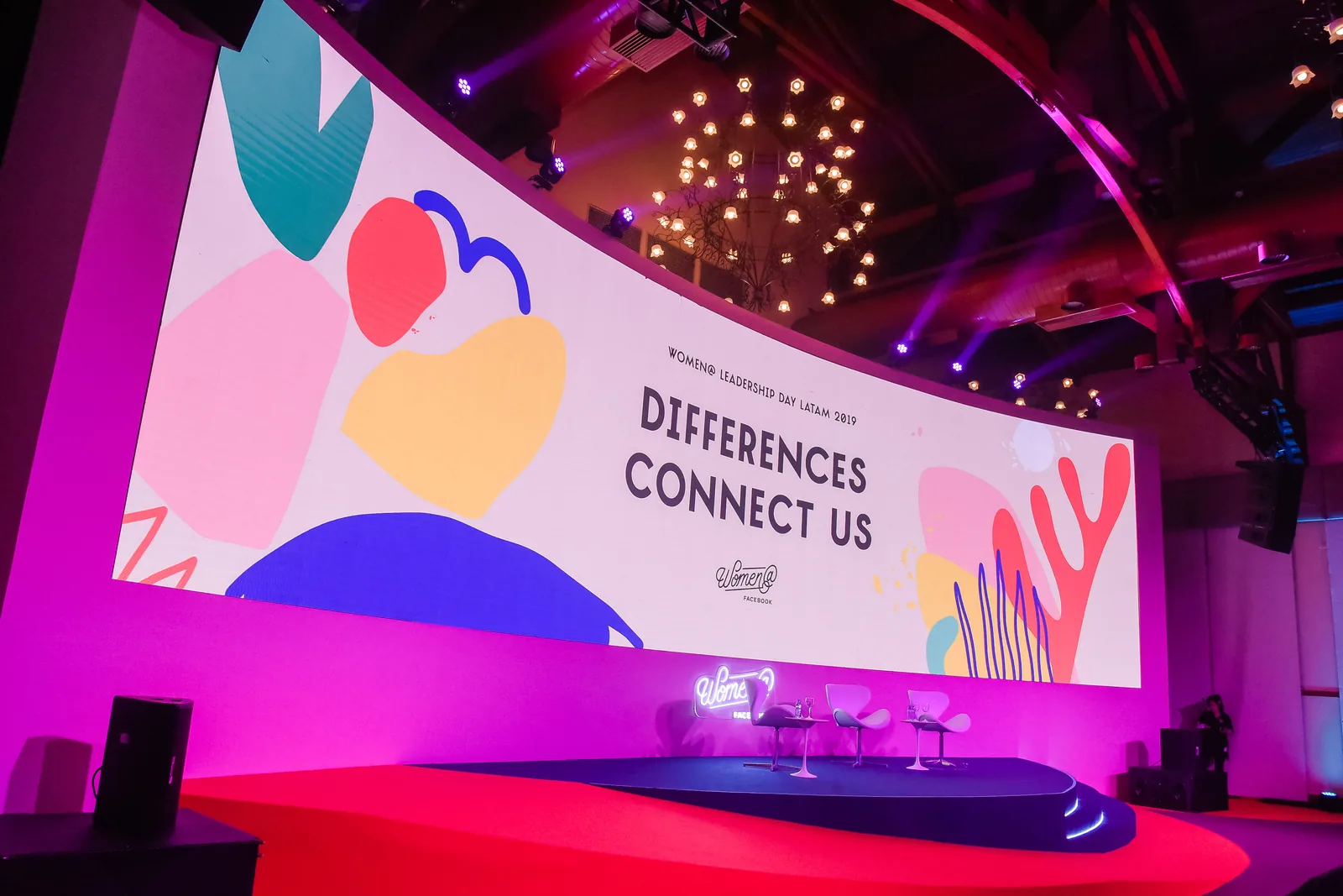 Curved stage screen wrapping the key visual's shapes around the room