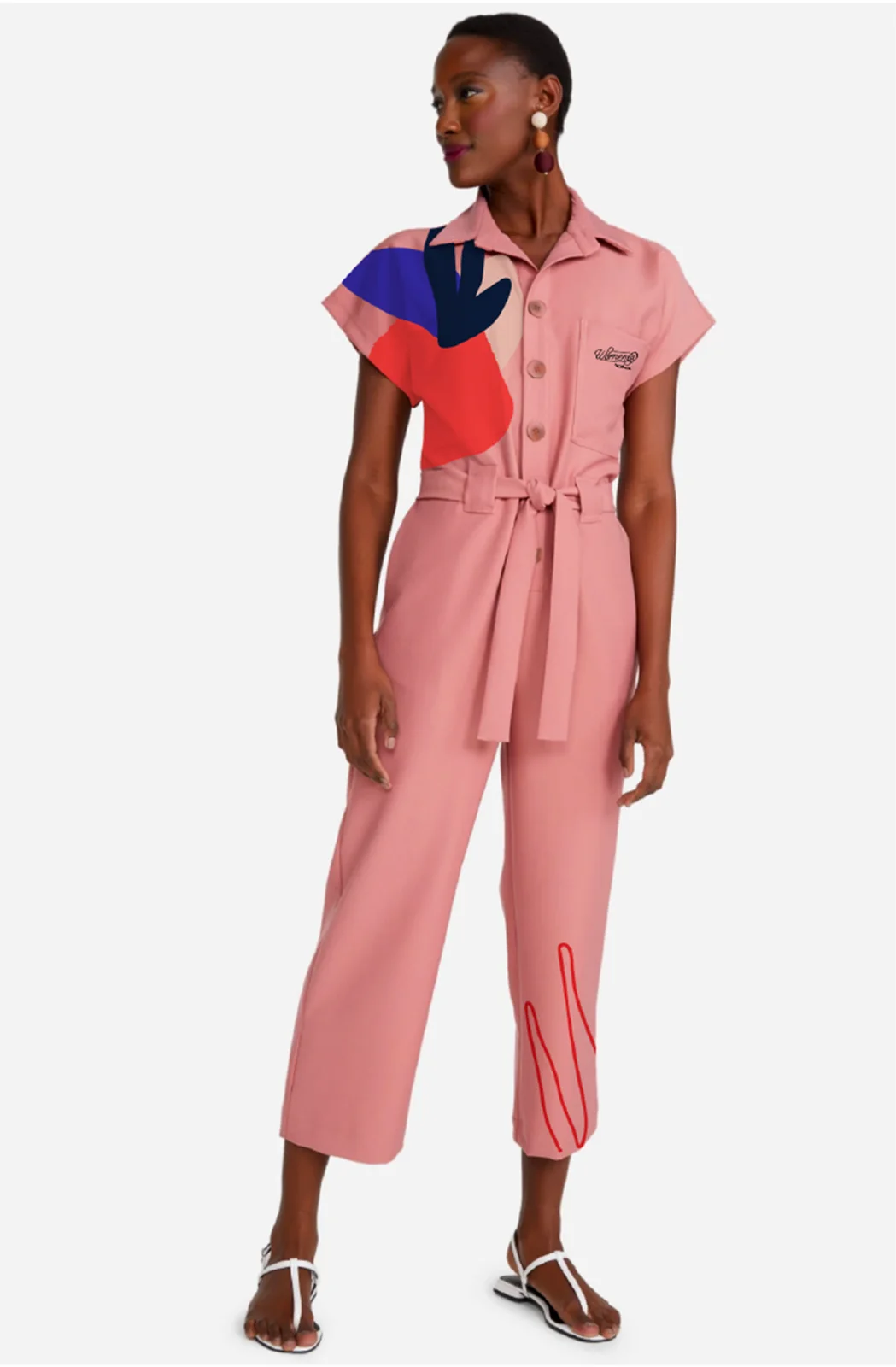 Uniform mockup: a muted pink jumpsuit with a key visual shape on the shoulder and a line drawing at the hem