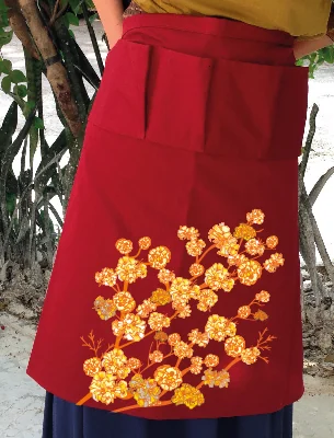 Red apron with the ipê branch printed at the hem