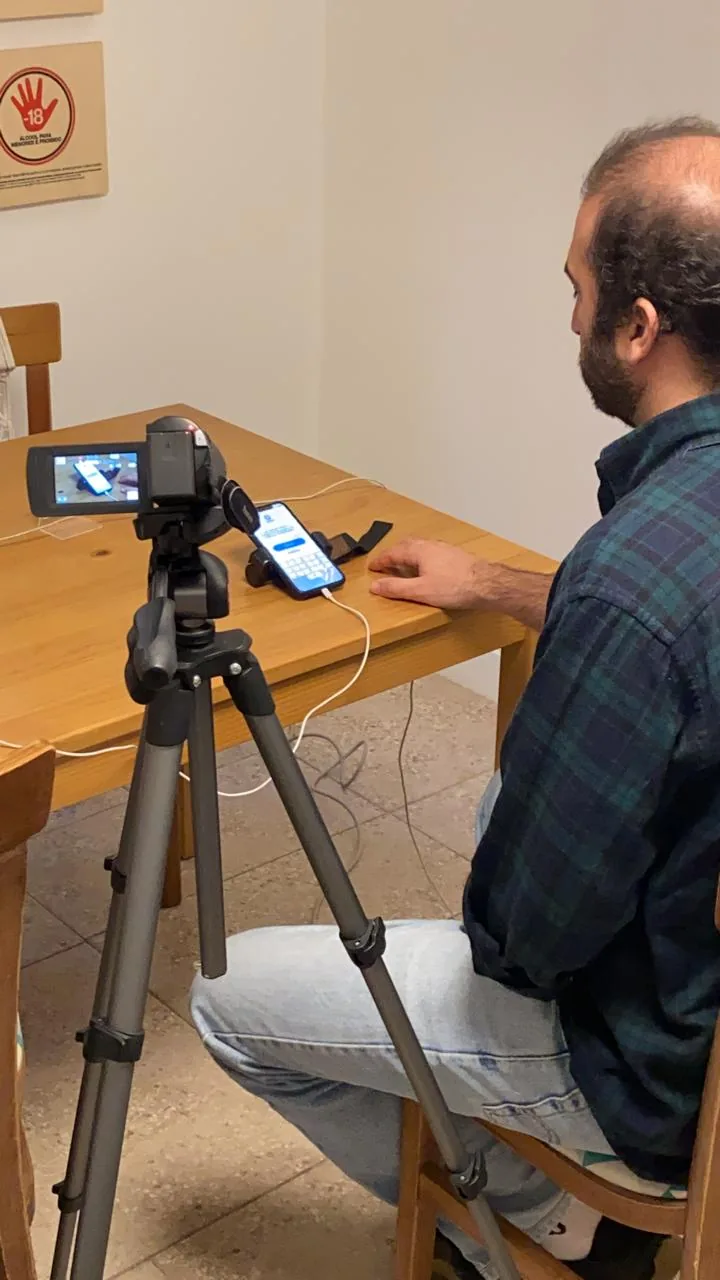 Usability test: a participant runs the prototype on a phone at a table, filmed by a camera on a tripod